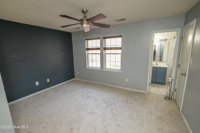 unfurnished bedroom featuring light colored carpet, a textured ceiling, and ensuite bathroom