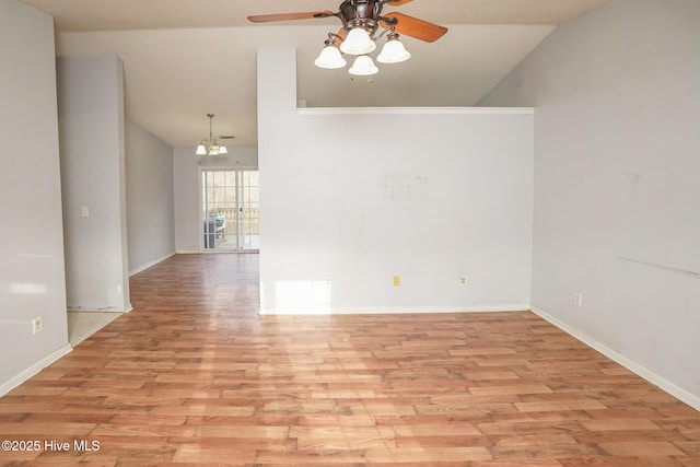 empty room featuring lofted ceiling, ceiling fan with notable chandelier, and light wood-type flooring