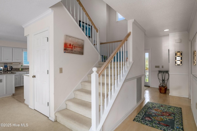 stairs with a healthy amount of sunlight, crown molding, and a textured ceiling