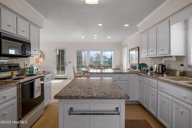 kitchen with sink, white cabinetry, crown molding, a kitchen island, and electric stove