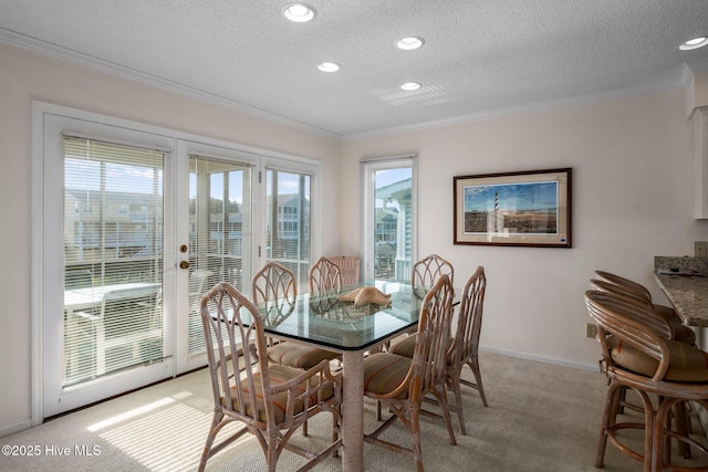 dining area with crown molding, light carpet, a textured ceiling, and french doors