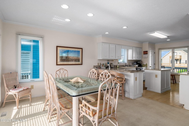 carpeted dining room featuring crown molding and sink