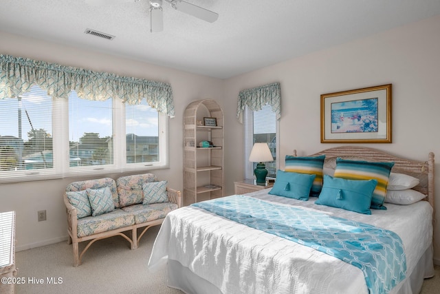 carpeted bedroom with ceiling fan and a textured ceiling