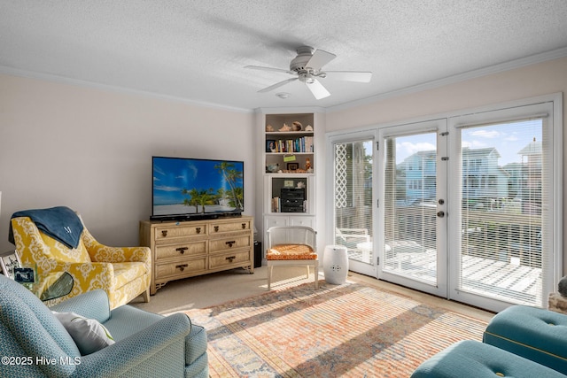 living room with ceiling fan, crown molding, light colored carpet, and a textured ceiling