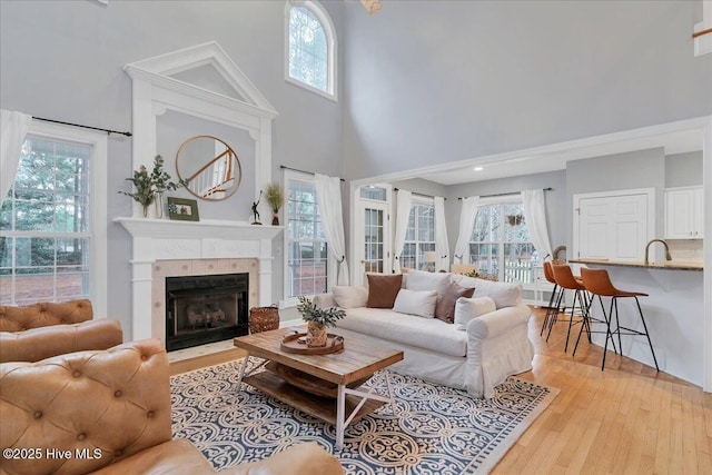 living room featuring a towering ceiling, a tile fireplace, and light wood-type flooring