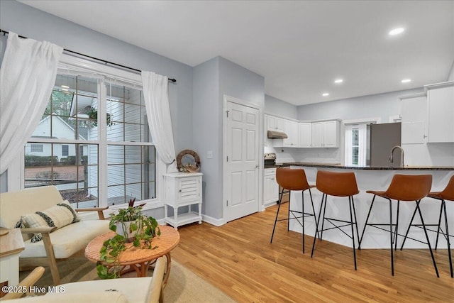 kitchen featuring white cabinetry, sink, kitchen peninsula, stainless steel appliances, and light wood-type flooring