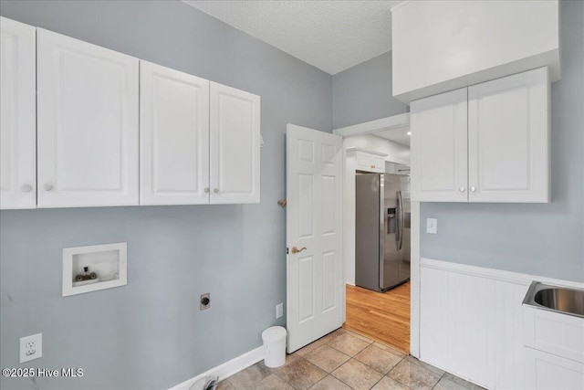 laundry area featuring sink, electric dryer hookup, hookup for a washing machine, cabinets, and a textured ceiling