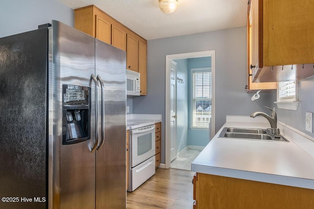 kitchen with white appliances, sink, light hardwood / wood-style flooring, and a textured ceiling