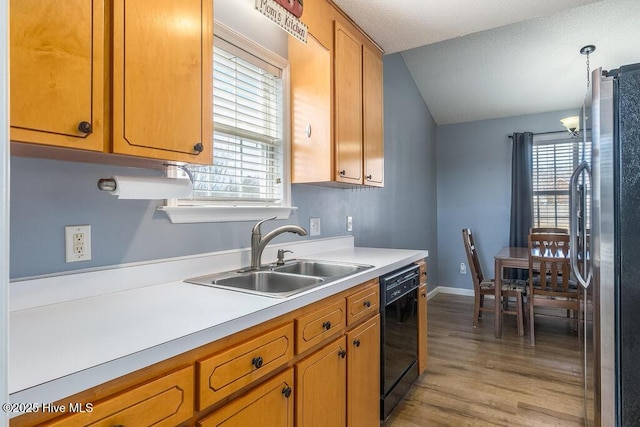 kitchen featuring pendant lighting, sink, stainless steel refrigerator, dishwasher, and light hardwood / wood-style floors