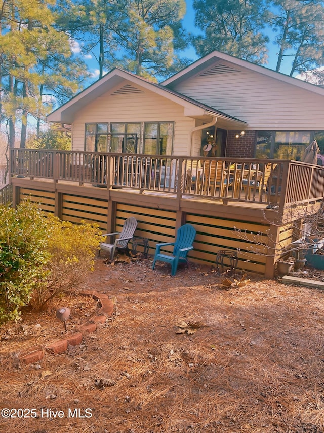 rear view of property featuring a wooden deck and a sunroom