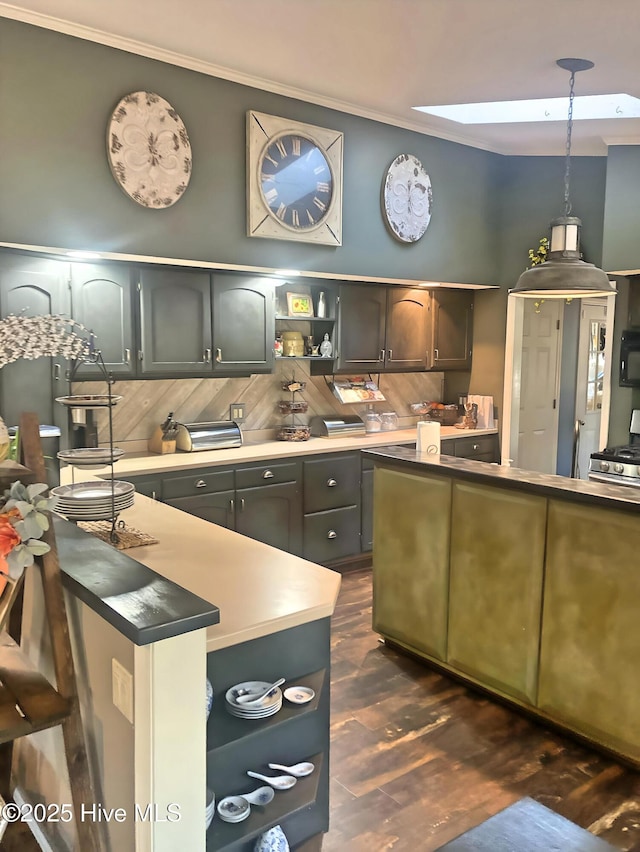 kitchen with crown molding, dark wood-type flooring, stainless steel gas range, tasteful backsplash, and decorative light fixtures