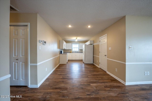 kitchen featuring dark hardwood / wood-style flooring, a textured ceiling, white cabinets, and white fridge