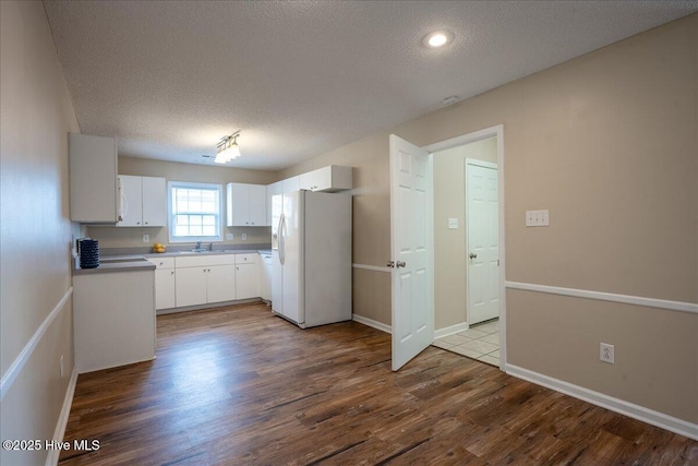 kitchen with sink, wood-type flooring, white refrigerator with ice dispenser, a textured ceiling, and white cabinets