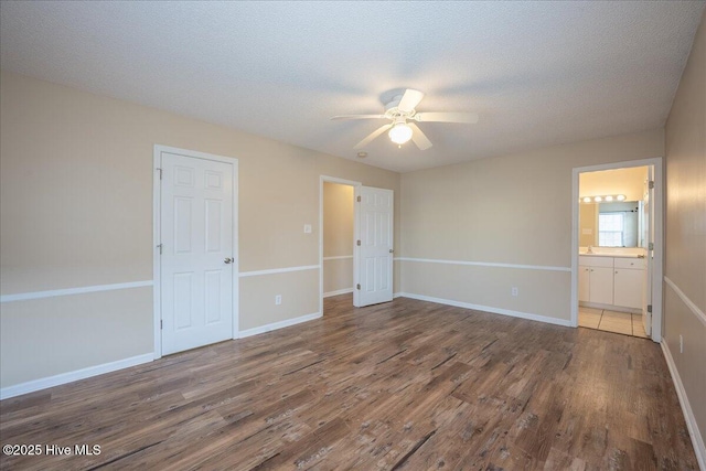 unfurnished bedroom with ceiling fan, a textured ceiling, dark hardwood / wood-style flooring, and ensuite bath