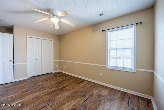 unfurnished bedroom featuring ceiling fan, a textured ceiling, dark hardwood / wood-style flooring, and a closet