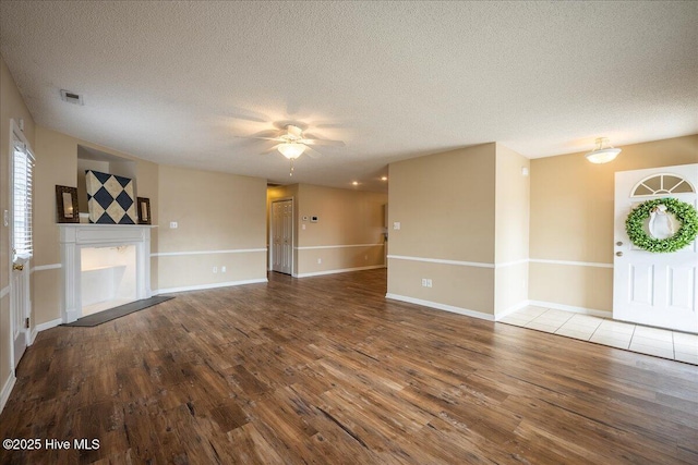 unfurnished living room with ceiling fan, hardwood / wood-style flooring, and a textured ceiling