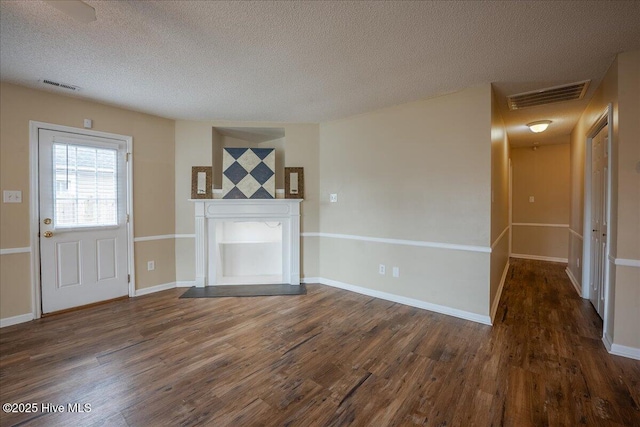 unfurnished living room with a textured ceiling and dark hardwood / wood-style flooring