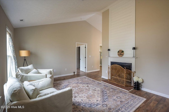 living room with high vaulted ceiling, dark wood-type flooring, a textured ceiling, and a fireplace