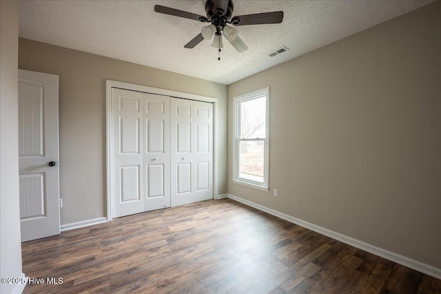 unfurnished bedroom with dark hardwood / wood-style flooring, ceiling fan, a closet, and a textured ceiling