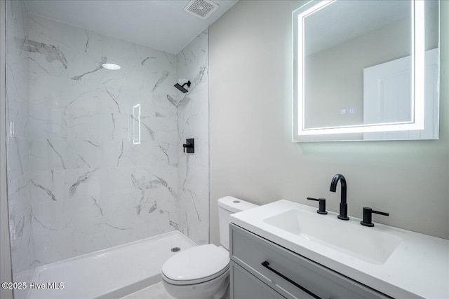 bathroom featuring vanity, toilet, and a tile shower