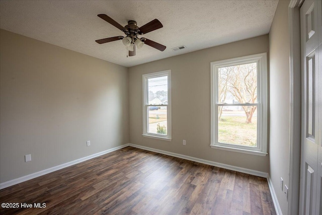 unfurnished room featuring dark wood-type flooring, plenty of natural light, and a textured ceiling