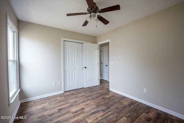 unfurnished bedroom with ceiling fan, dark wood-type flooring, a closet, and a textured ceiling