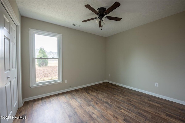 empty room featuring ceiling fan, dark hardwood / wood-style floors, and a textured ceiling