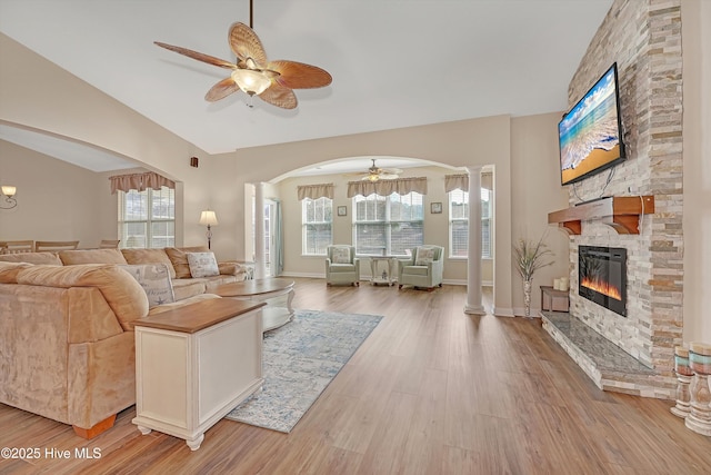 living room featuring ornate columns, ceiling fan, a fireplace, and light hardwood / wood-style floors