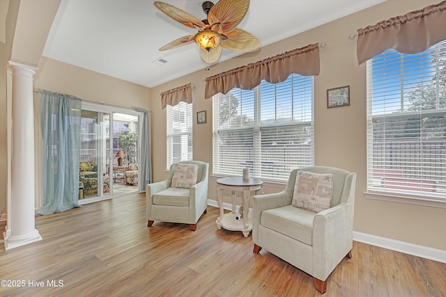 sitting room featuring plenty of natural light, light wood-type flooring, and ornate columns