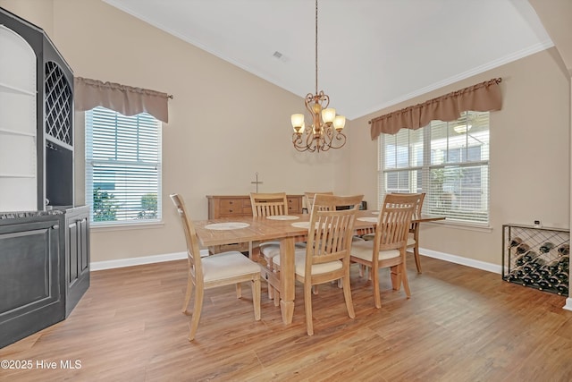 dining area featuring lofted ceiling, light hardwood / wood-style flooring, ornamental molding, and an inviting chandelier