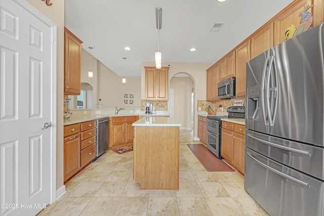 kitchen featuring appliances with stainless steel finishes, a center island, tasteful backsplash, decorative light fixtures, and kitchen peninsula