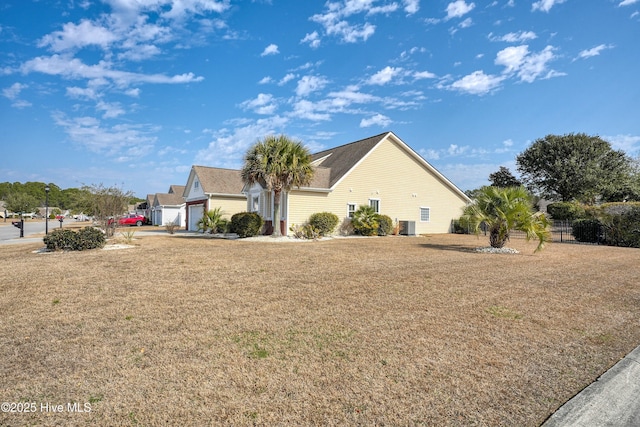 view of side of property with a garage, a yard, and central air condition unit