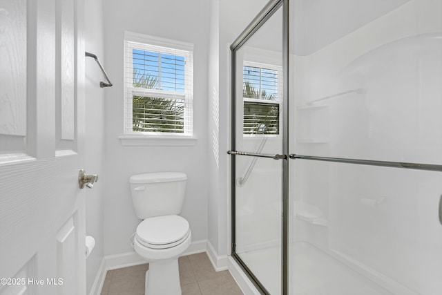 bathroom featuring tile patterned flooring, a shower with shower door, and toilet