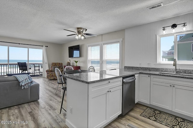 kitchen with white cabinetry, a water view, dark stone countertops, and kitchen peninsula