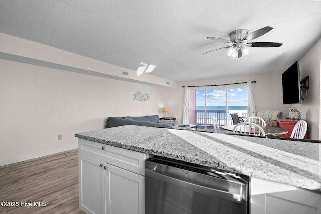 kitchen with a textured ceiling, baseboards, white cabinets, light wood-style floors, and dishwasher