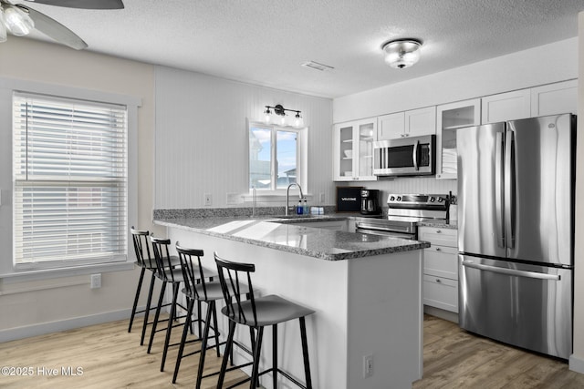 kitchen with visible vents, a breakfast bar area, appliances with stainless steel finishes, a peninsula, and a sink