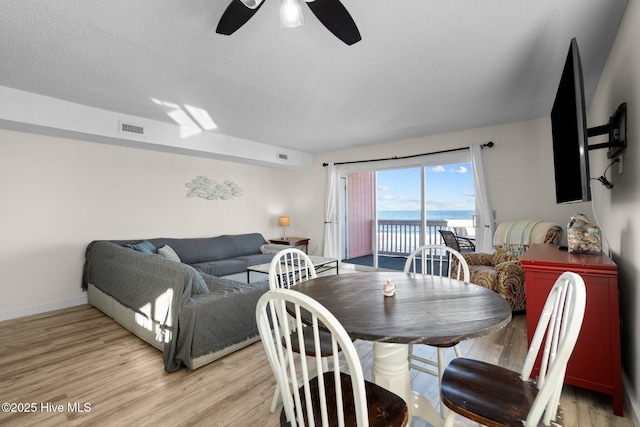 dining room featuring light wood-style flooring, visible vents, ceiling fan, and baseboards