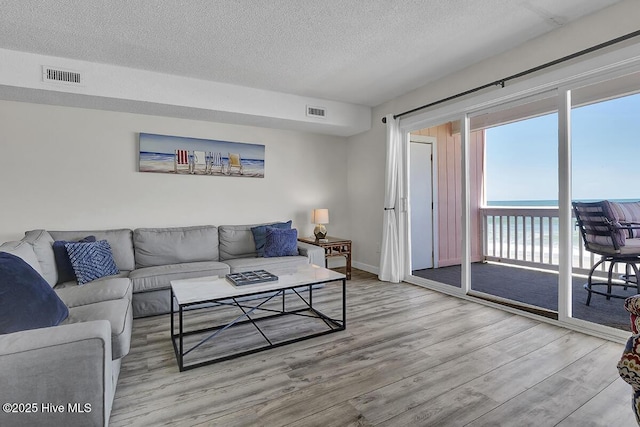 living room featuring a water view, a textured ceiling, and light wood-type flooring