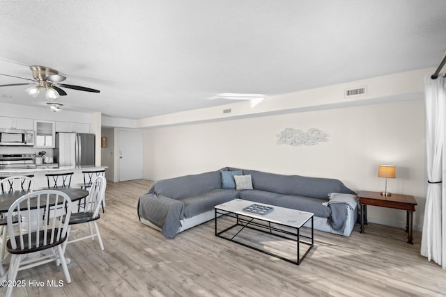 living area with visible vents, ceiling fan, and light wood finished floors