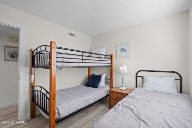 bedroom featuring visible vents, baseboards, and wood finished floors