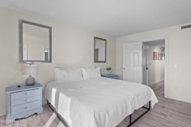 bedroom featuring baseboards, visible vents, and wood finished floors