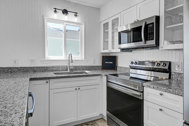 kitchen featuring stainless steel appliances, light stone countertops, sink, and white cabinets