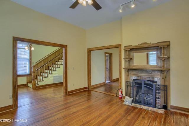 unfurnished living room featuring hardwood / wood-style flooring, ceiling fan, and rail lighting