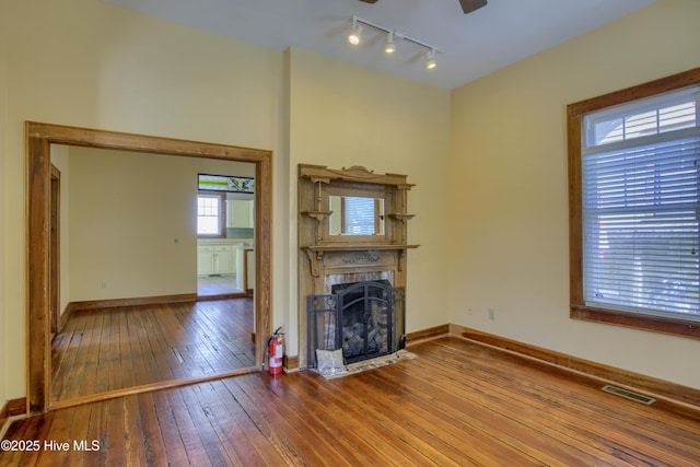 unfurnished living room with hardwood / wood-style flooring, track lighting, and ceiling fan