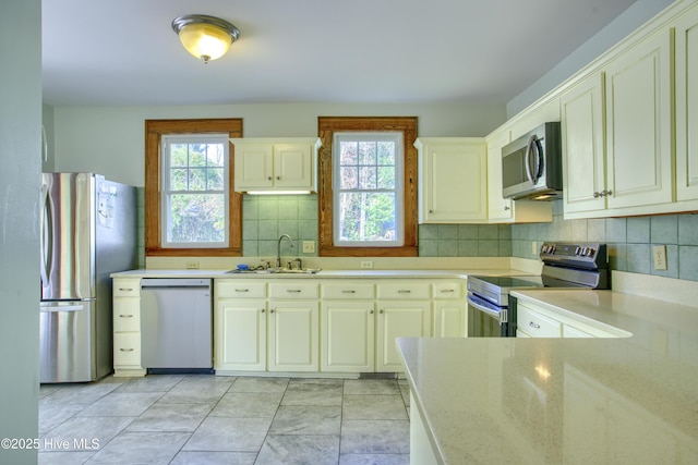 kitchen with tasteful backsplash, a healthy amount of sunlight, appliances with stainless steel finishes, and sink