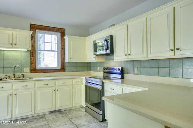 kitchen featuring sink, backsplash, light tile patterned flooring, and appliances with stainless steel finishes