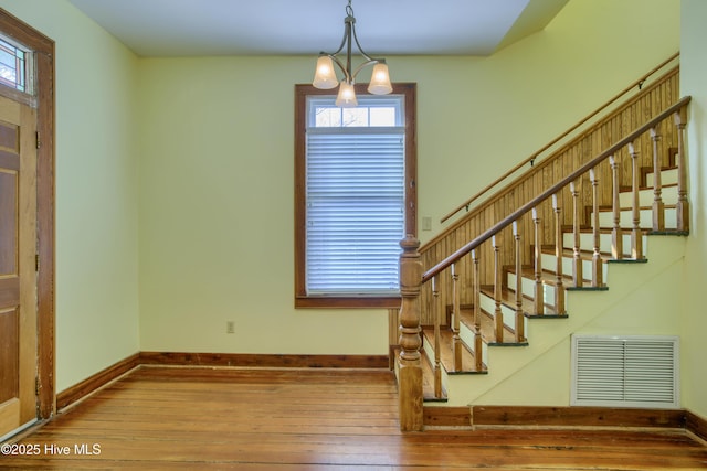 stairway featuring wood-type flooring and a notable chandelier