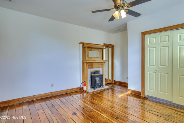 unfurnished living room featuring light hardwood / wood-style flooring, ceiling fan, and a wood stove