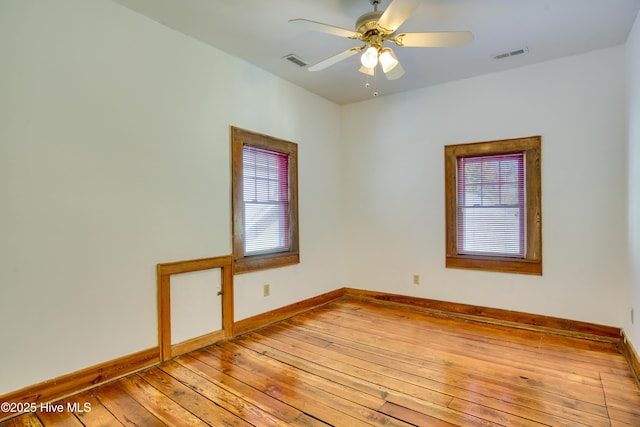 empty room with ceiling fan, wood-type flooring, and a wealth of natural light