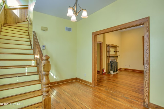 staircase with hardwood / wood-style flooring and a notable chandelier